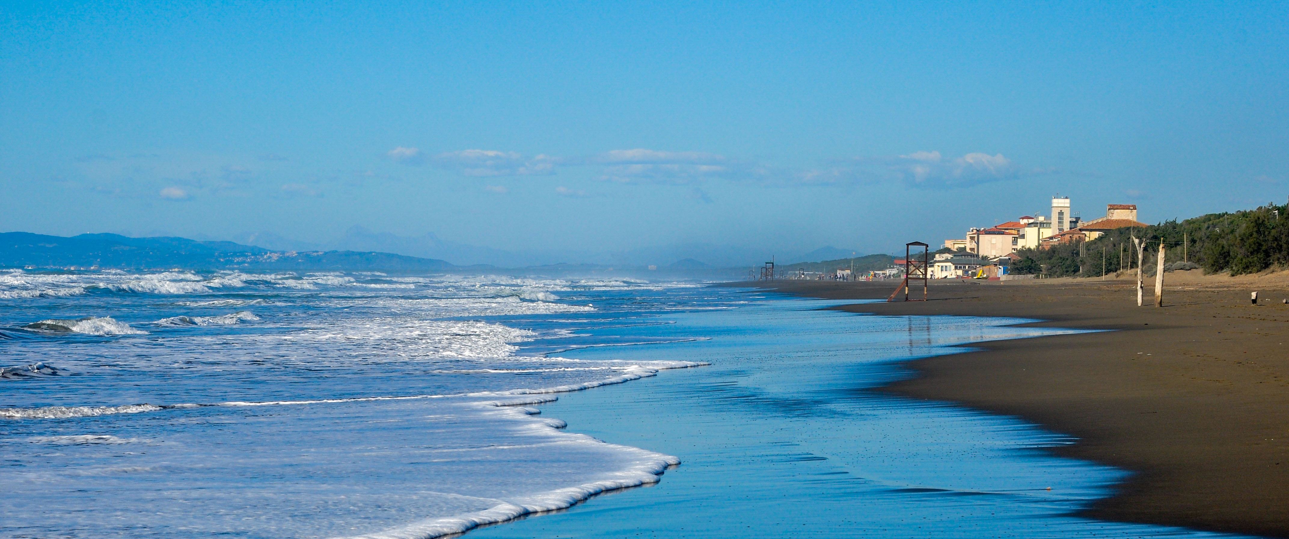 Waves along the shoreline and villas beside the beach.